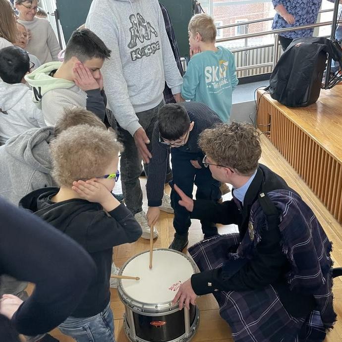 Schülerinnen und Schüler dürfen die Trommel ausprobieren. (vergrößerte Bildansicht wird geöffnet)