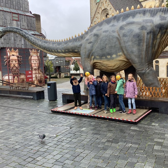 Schülerinnen und Schüler mit Dinosaurier vor dem Dom (vergrößerte Bildansicht wird geöffnet)